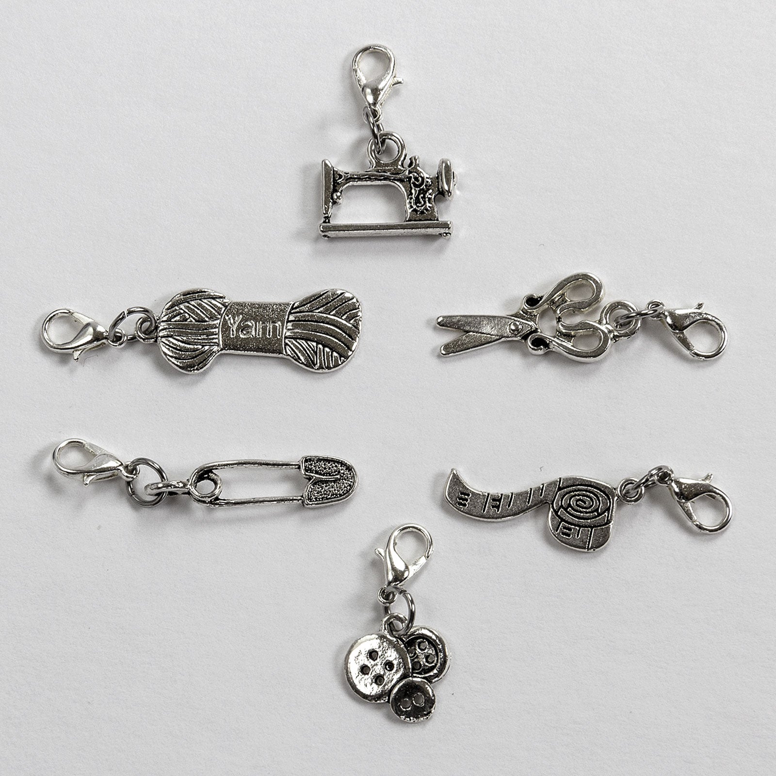 locking stitch marker charms include a sewing machine, yarn hank, scissors, safety pin, measuring tape, and buttons