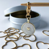 Metallic gold heart-shaped stitch markers with an enameled gold charm