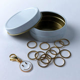 12 gold circle stitch markers with bonus smiliey face charm progress keeper in a white and gold storage case