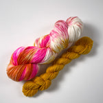 pink, white, mustard, peach, and orange full sized yarn skein and a butterscotch mini