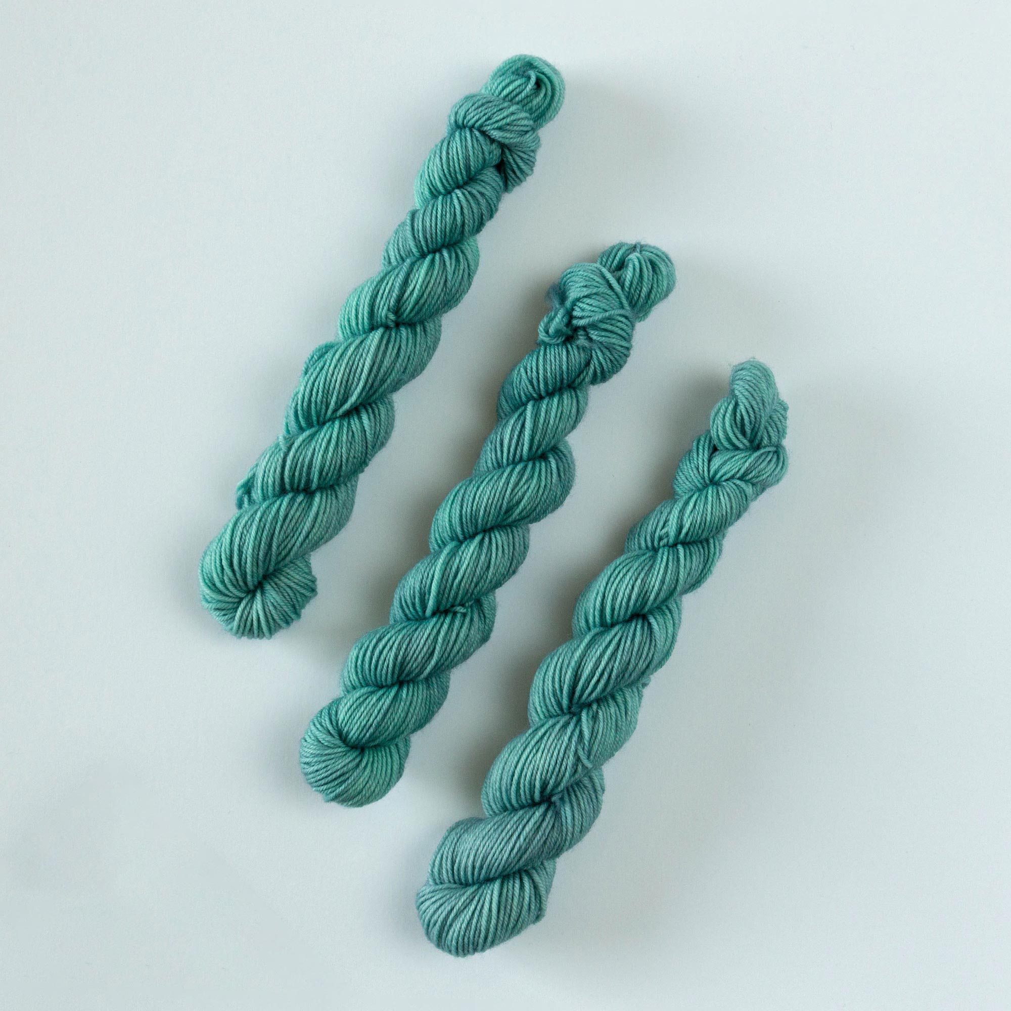 trio of fingering weight mini skeins in teal "shipwreck" colorway