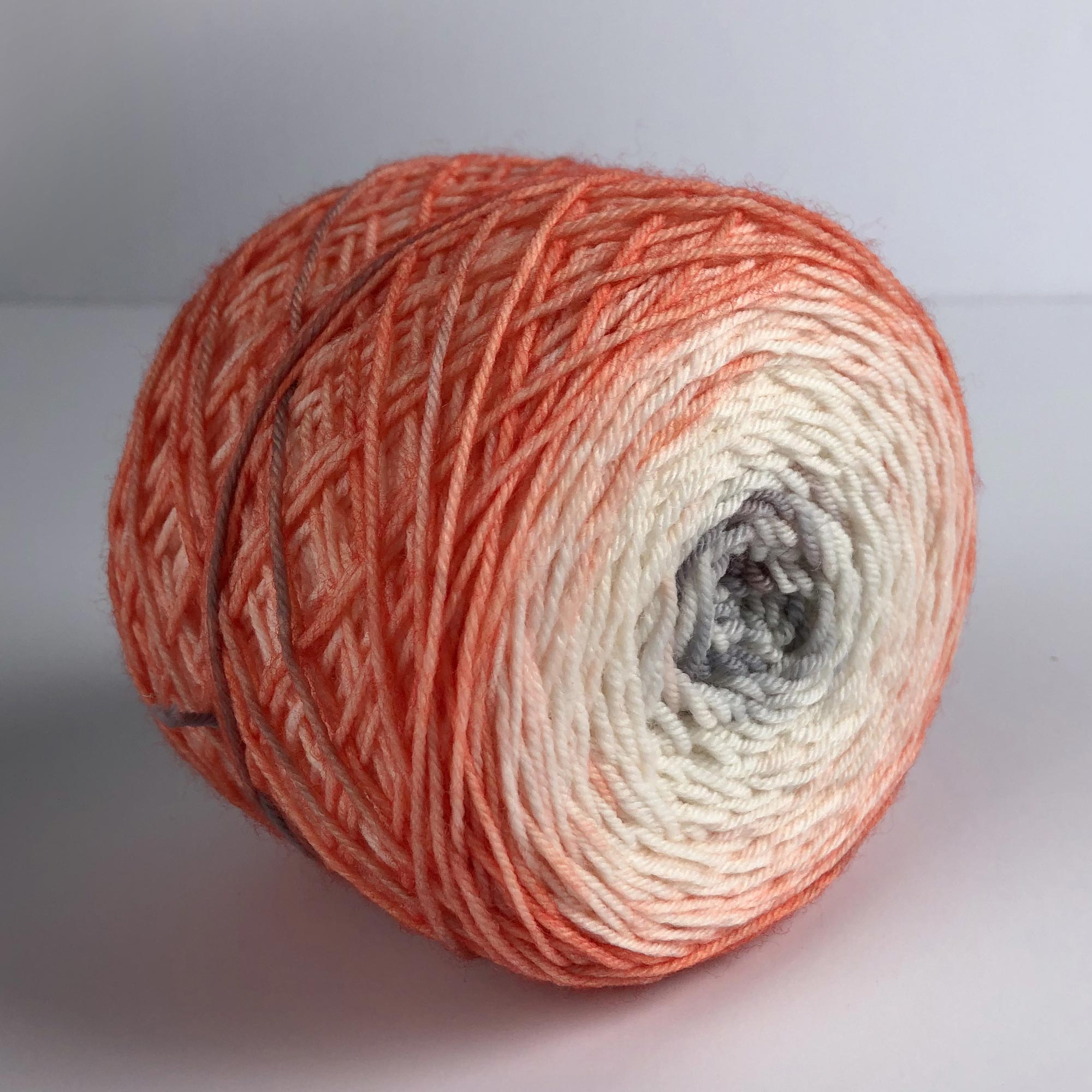 center pull cake of coral and gray gradient space dyed fingering weight yarn