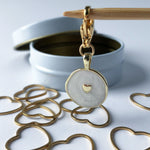 Metallic gold heart-shaped stitch markers with an enameled gold charm 