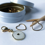 close-up of metal stitch marker set with heart charm and storage tin