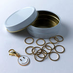 12 gold circle stitch markers with bonus smiliey face charm progress keeper in a white and gold storage case